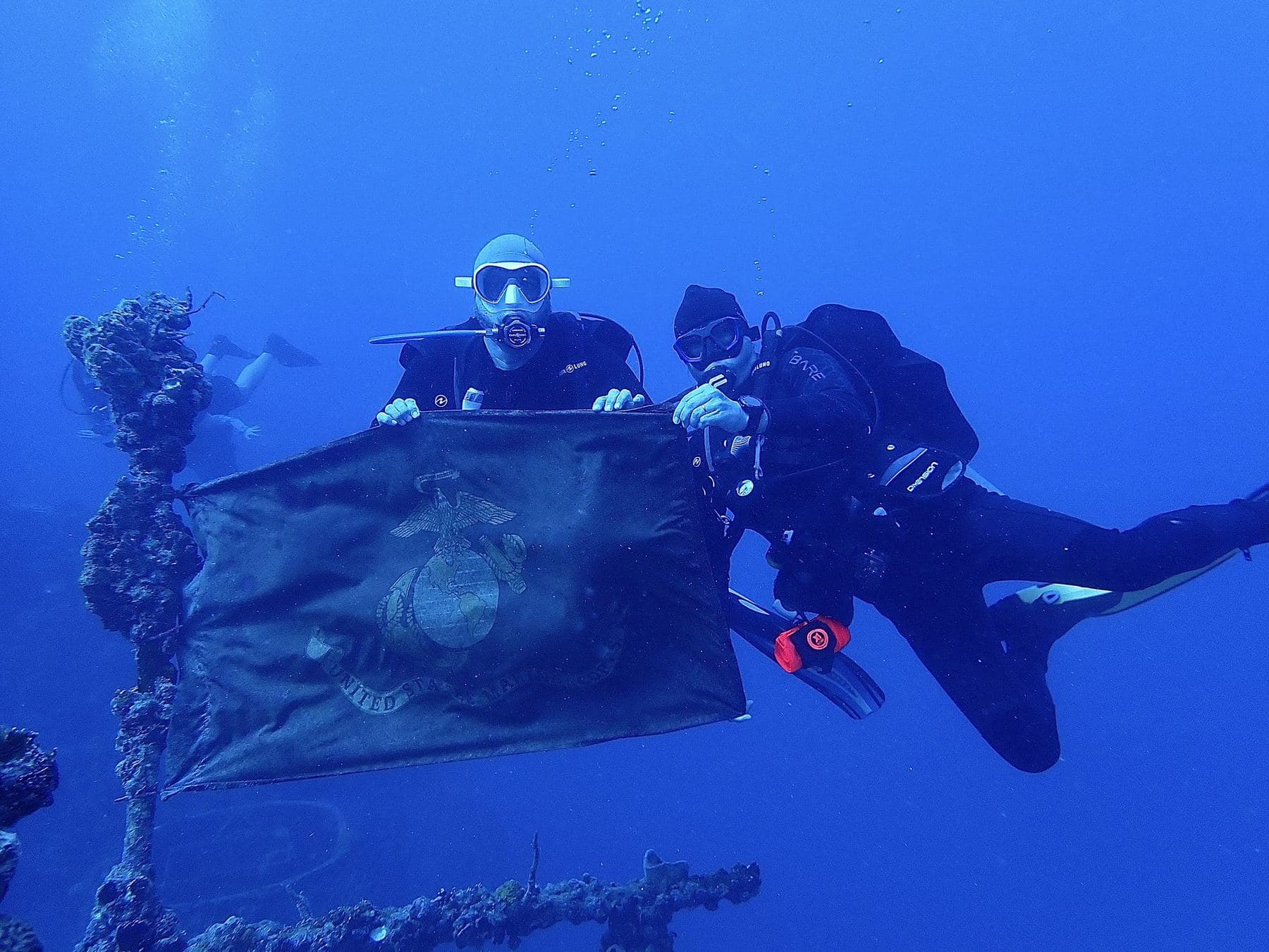 Two divers with a Marine Corps flag on the wreck