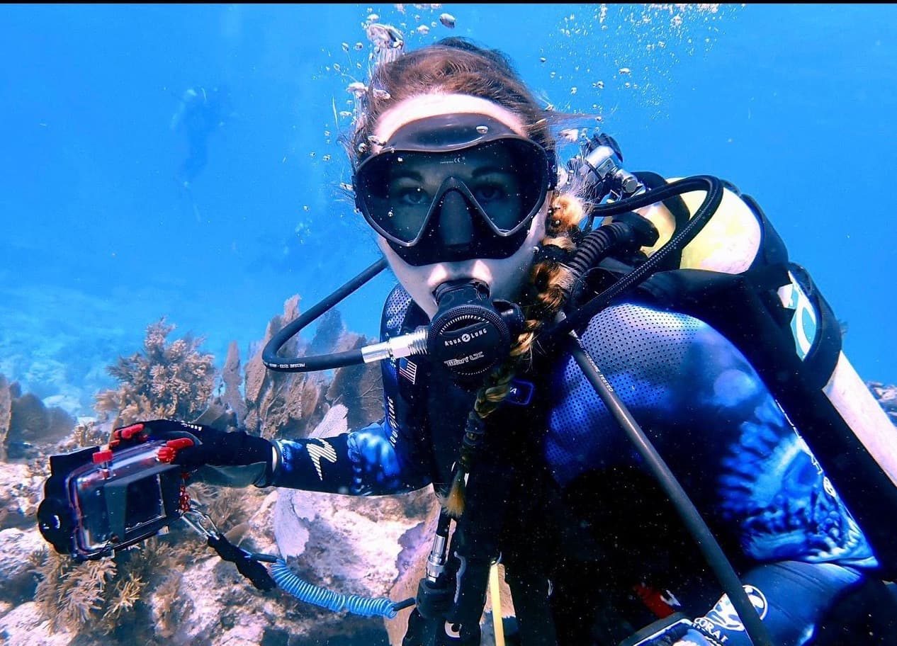 Jessica Hanjora diving with her camera over a coral reef